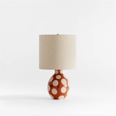 an orange and white polka dot table lamp with a linen shade on the base,