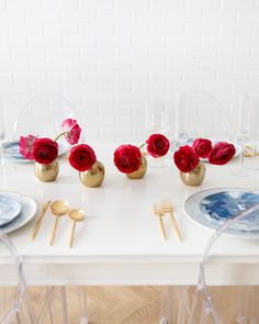 the table is set with red roses and gold cutlery, plates and utensils