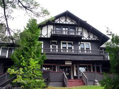 a large black and white house with lots of windows on the second floor is surrounded by trees