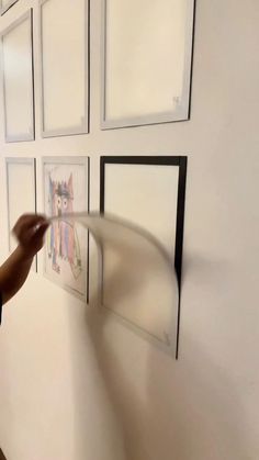 a person is painting pictures on the wall with white paint and black frame around them