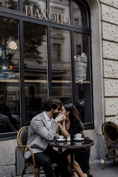 two people sitting at a table in front of a store