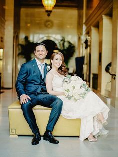 a bride and groom are sitting on a bench in the lobby at their wedding reception