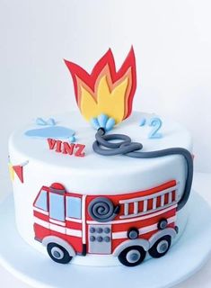 a white cake with a red fire truck on it's side and flames coming out of the top