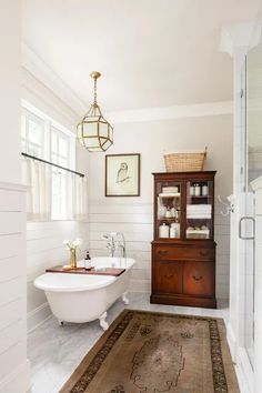 a white bath tub sitting next to a wooden cabinet