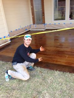 a man kneeling down on the ground next to a wooden floor with tape around it