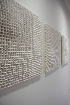 three pieces of art hanging on the wall in an office building, one is made out of white paper