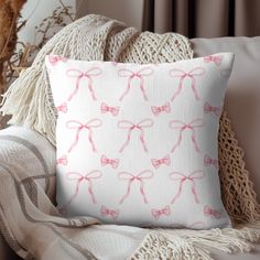 a pink bow pillow sitting on top of a couch next to a white throw pillow