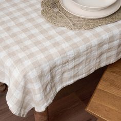 the table is set with white plates and silverware on it, along with a wicker basket