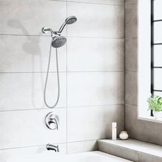 a white bath tub sitting under a window next to a sink and shower faucet