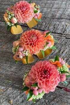 three small vases filled with flowers on top of a wooden table