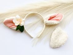 two white and pink bunny ears are laying on top of a furry tail, with a flower in the middle