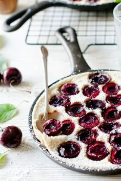 two pans filled with pie and cherries next to each other on a table