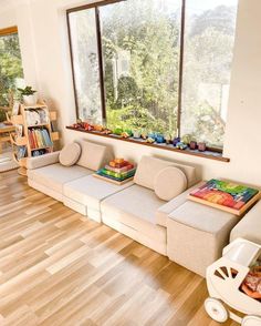 a living room filled with lots of furniture next to a wooden floor covered in books