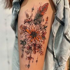 a woman's arm with an orange flower and feathers tattoo on the left upper arm