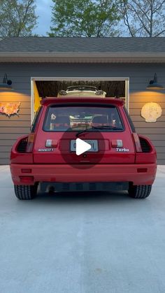 a red car is parked in front of a garage with its door open and the roof opened