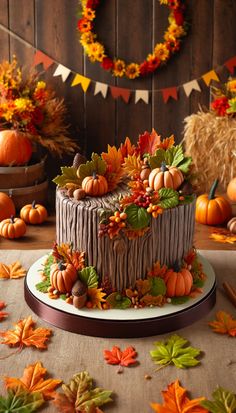 a decorated cake sitting on top of a table covered in fall leaves and pumpkins