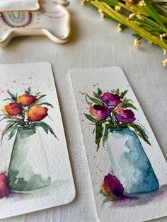 two watercolor paintings of vases with flowers in them on top of a table