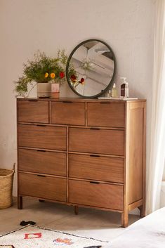 a bedroom with a dresser, mirror and rug on the floor in front of it