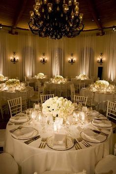 a table with white flowers and candles is set up for a formal dinner or reception