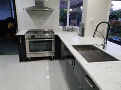 a kitchen with white marble counter tops and stainless steel appliances in front of an open window