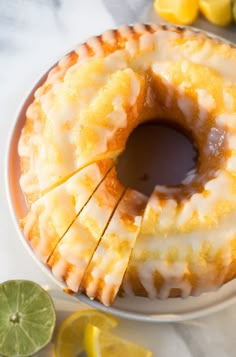 a lemon bundt cake on a plate next to sliced lemons and limes