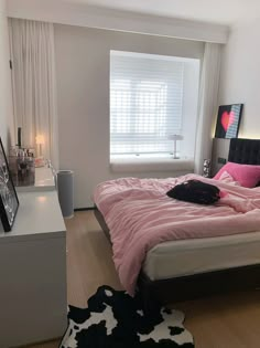 a bed room with a neatly made bed next to a window and a cow rug