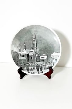 a black and white photo of a plate with a cityscape on the front