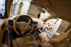 the interior of a car with tan leather seats and steering wheel controls, looking down at an alleyway