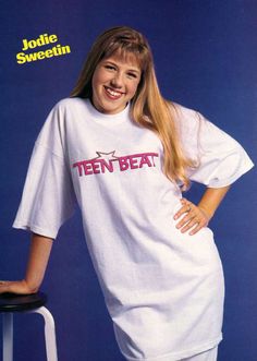 a woman in white shirt and shorts posing for a magazine cover with her legs crossed