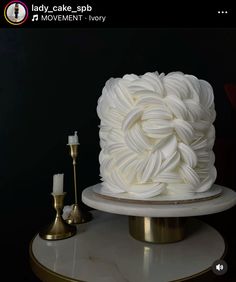 a white cake sitting on top of a table next to a candle