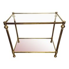 a brass and glass side table with two shelves on each side, one shelf holding a mirror