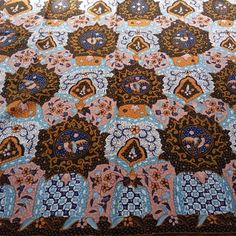 an intricately designed quilt is displayed on a tablecloth with blue and orange designs