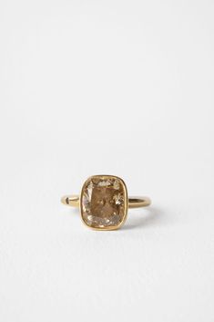 a gold ring with a large brown stone in the center on a white tablecloth