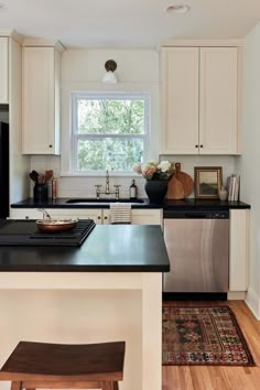 a kitchen with white cabinets and black counter tops, an island in front of the sink