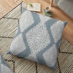 a blue and white floor pillow sitting on top of a rug next to a chair