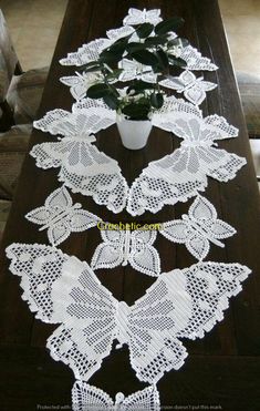 a table with white lace on it and a potted plant