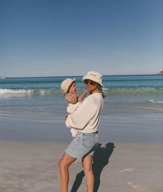 a woman holding a baby on the beach