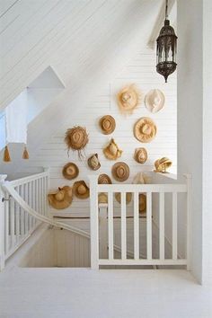 there are many hats hanging on the wall in this white room and it looks like they have been made out of wood