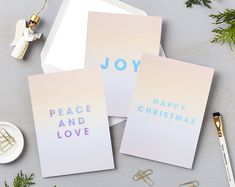 three greeting cards with the words joy, peace and christmas written on them next to office supplies