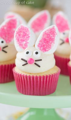 cupcakes with bunny ears and pink frosting are on a green cake plate