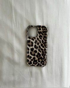 a cell phone case sitting on top of a white sheet covered in animal print fabric