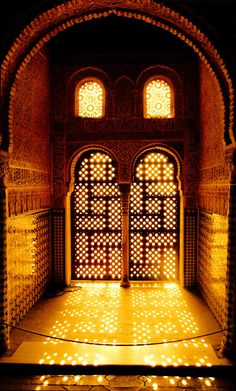 the light is shining on the floor in front of an ornate doorway with arched windows