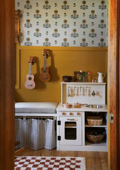 a small kitchen with an oven, stove and toy guitar hanging on the wall next to it