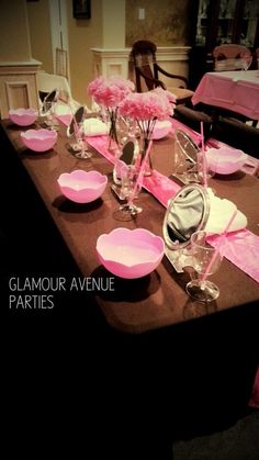 the table is set with pink flowers and place settings for guests to sit down at