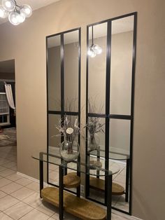 a glass table with two vases on it and some flowers in front of the mirror