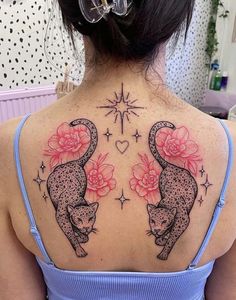 the back of a woman's shoulder with two cats and flowers on it