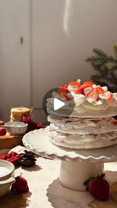 a stack of cake sitting on top of a table next to plates and bowls filled with strawberries