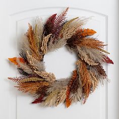 a white door with a wreath made out of dried grass and leaves hanging on it