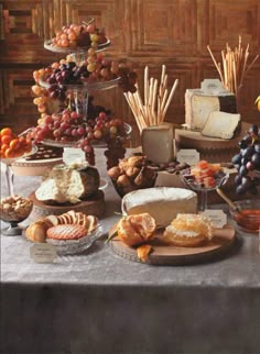 a table topped with lots of different types of cheeses and fruit on top of plates