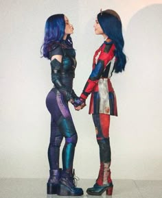 two women dressed in costumes are standing next to each other holding hands and looking into each other's eyes